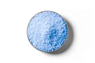 Light blue Flexi N (nBPT) coated urea fertiliser granules in a round dish